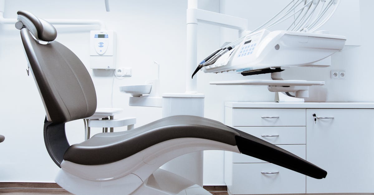 A modern dental clinic interior showcasing a dental chair and equipment in a clean, clinical setting.